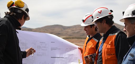 Profesionales con cascos revisando planos en una obra