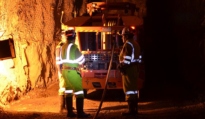 Trabajadores con ropa de alta visibilidad junto a un camión en un túnel