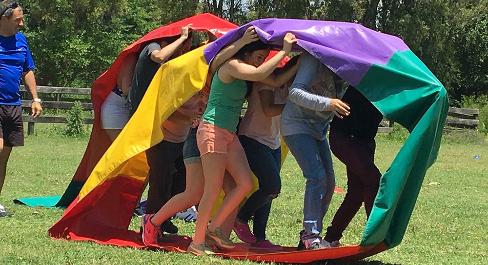 Grupo realizando una dinámica al aire libre con una tela de colores